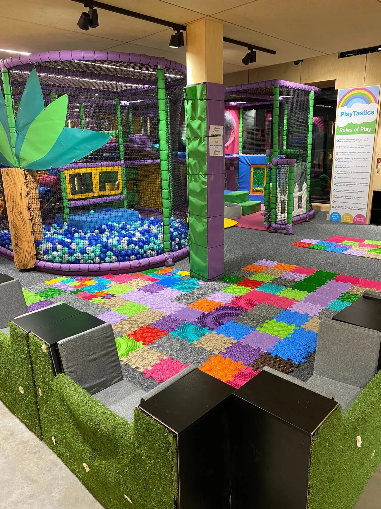 Indoor play centre with colourful soft play structures, ball pit, climbing frames and foam floor tiles in bright primary colours.