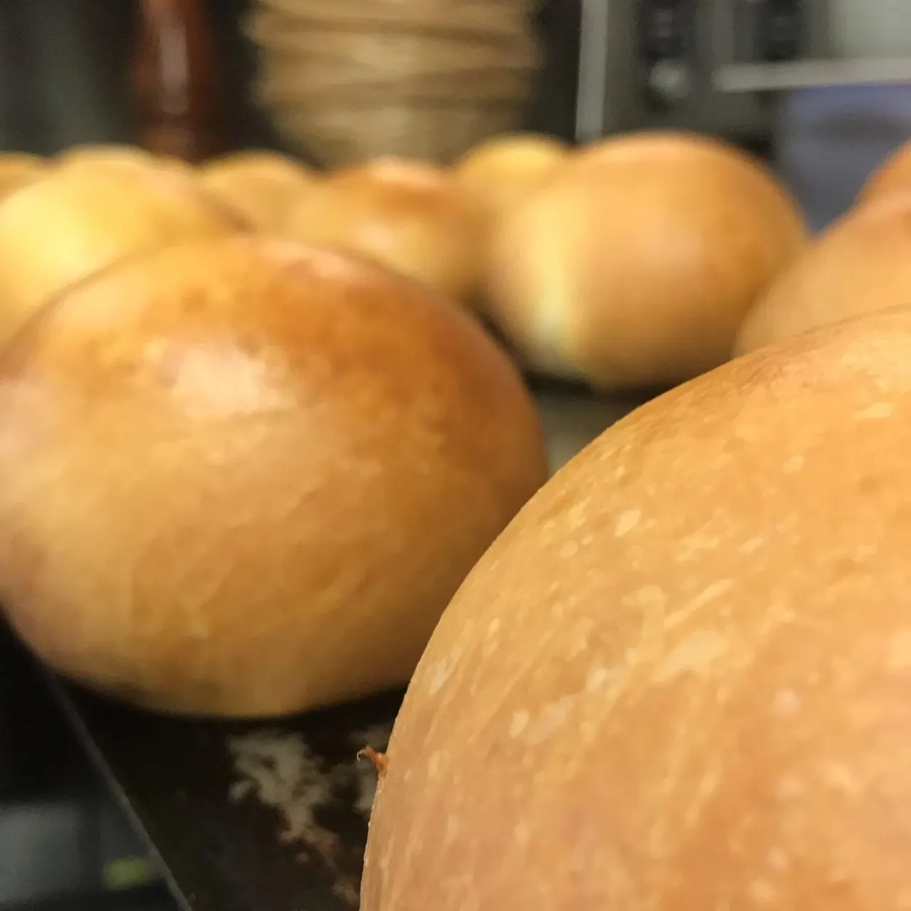 Close-up of freshly baked bread rolls with golden-brown crusts on a kitchen surface.