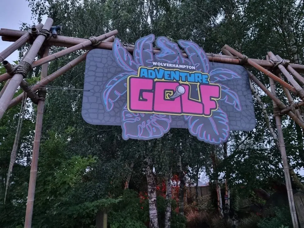 Colourful signage for an adventure golf attraction surrounded by trees and natural woodland.