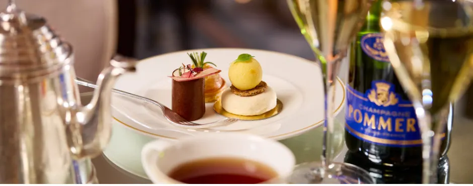 Fine dining table setting with plated desserts, champagne bottle and soup course.