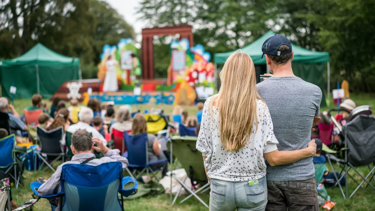 Outdoor family event with crowds seated on grass watching colourful inflatable play structures and entertainment under green marquees.