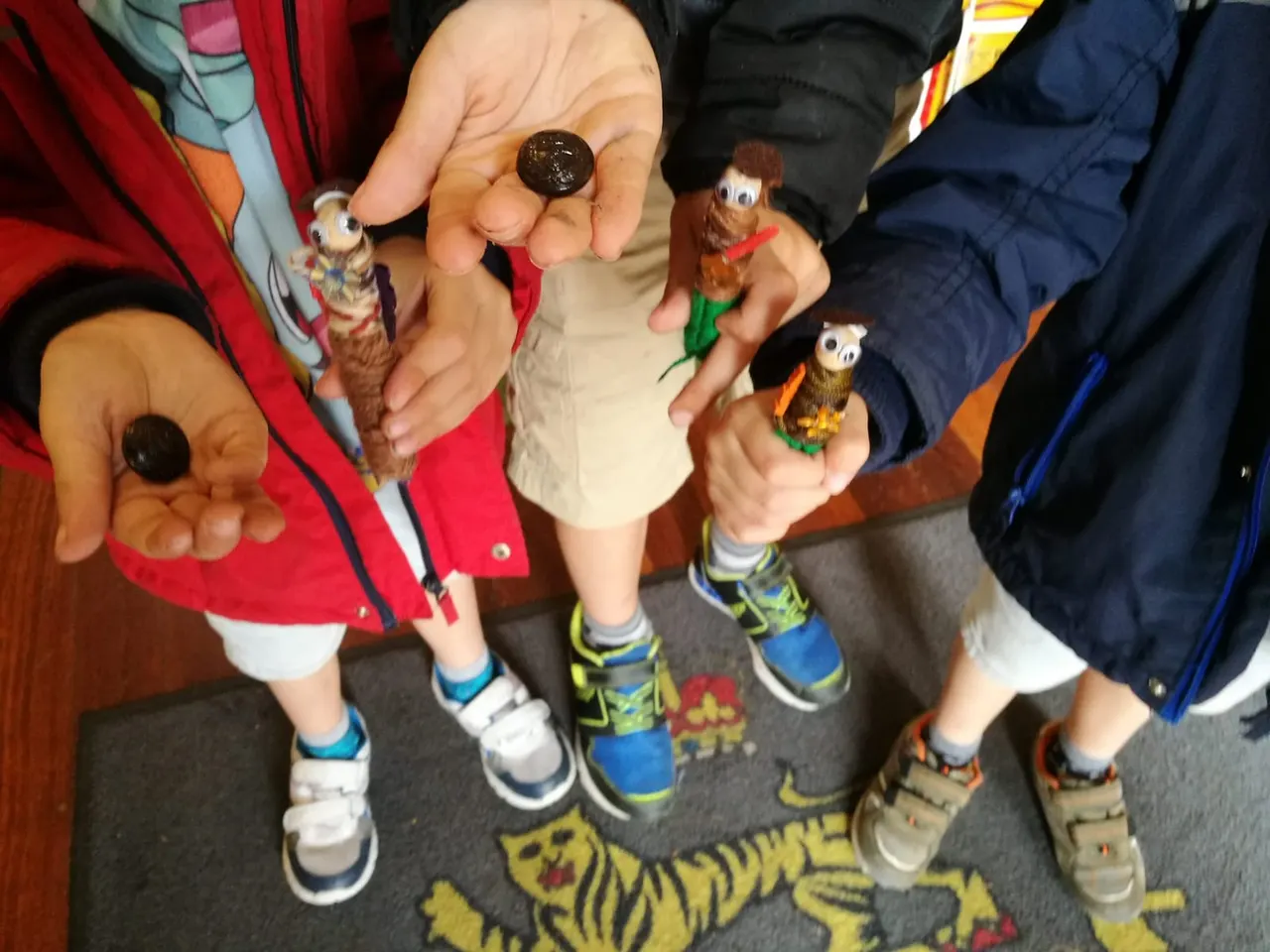 Adults and children holding small toy birds and a bronze medal during a hands-on museum activity.