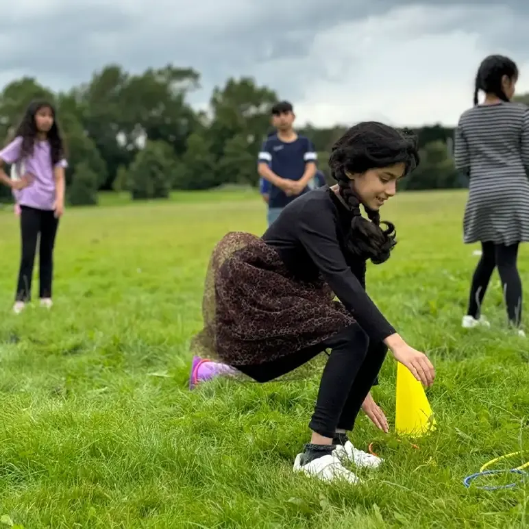Children playing frisbee golf in a green field during outdoor activity time.