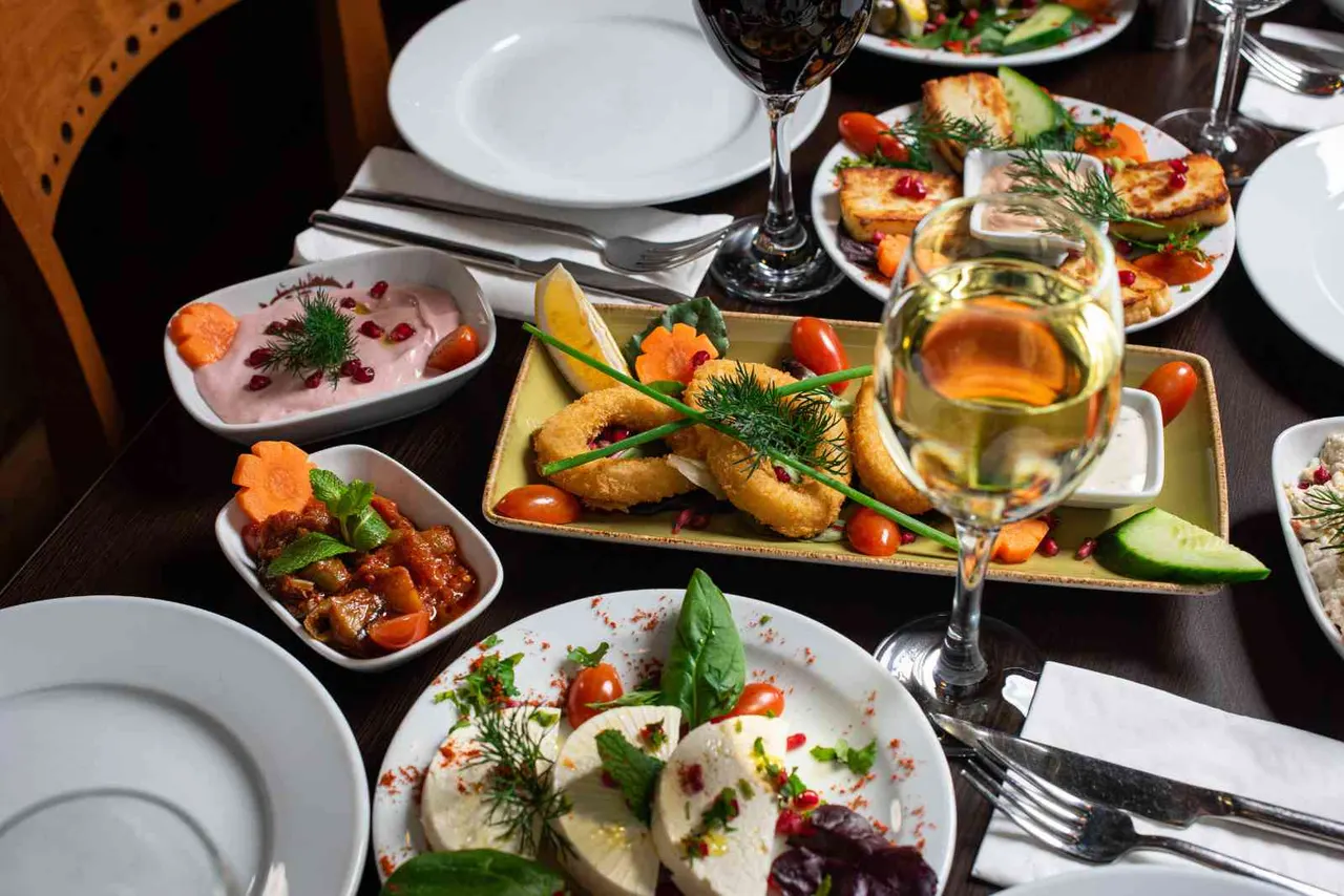 Fine dining table spread with multiple plated dishes, wine glasses, and cutlery at a restaurant.