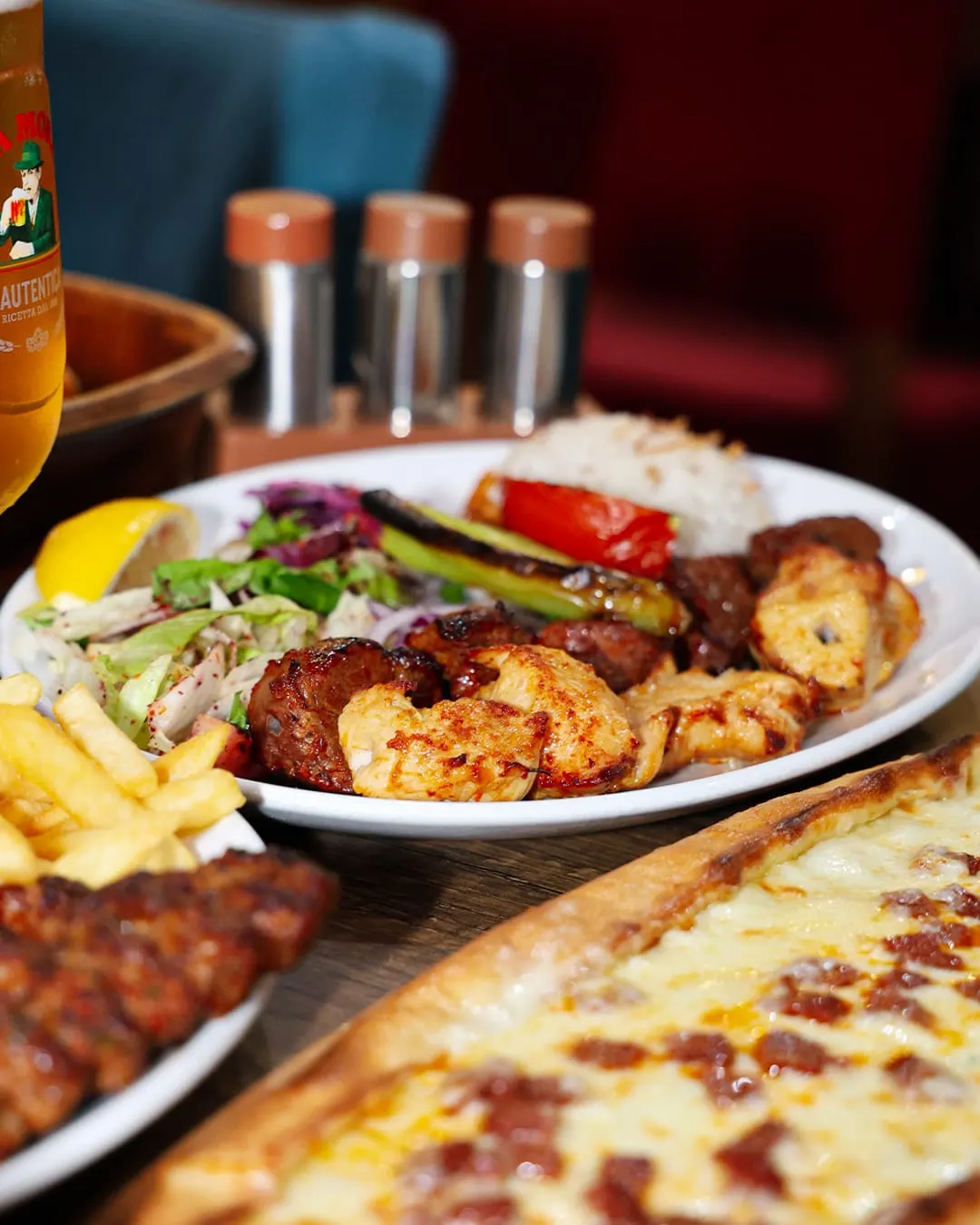Grilled meat and seafood skewers with salad, fries and flatbread on a restaurant table.