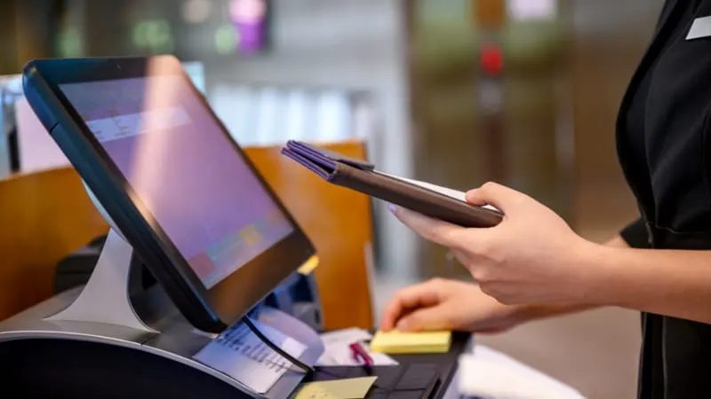 Person using a stylus to interact with a touchscreen display panel indoors.