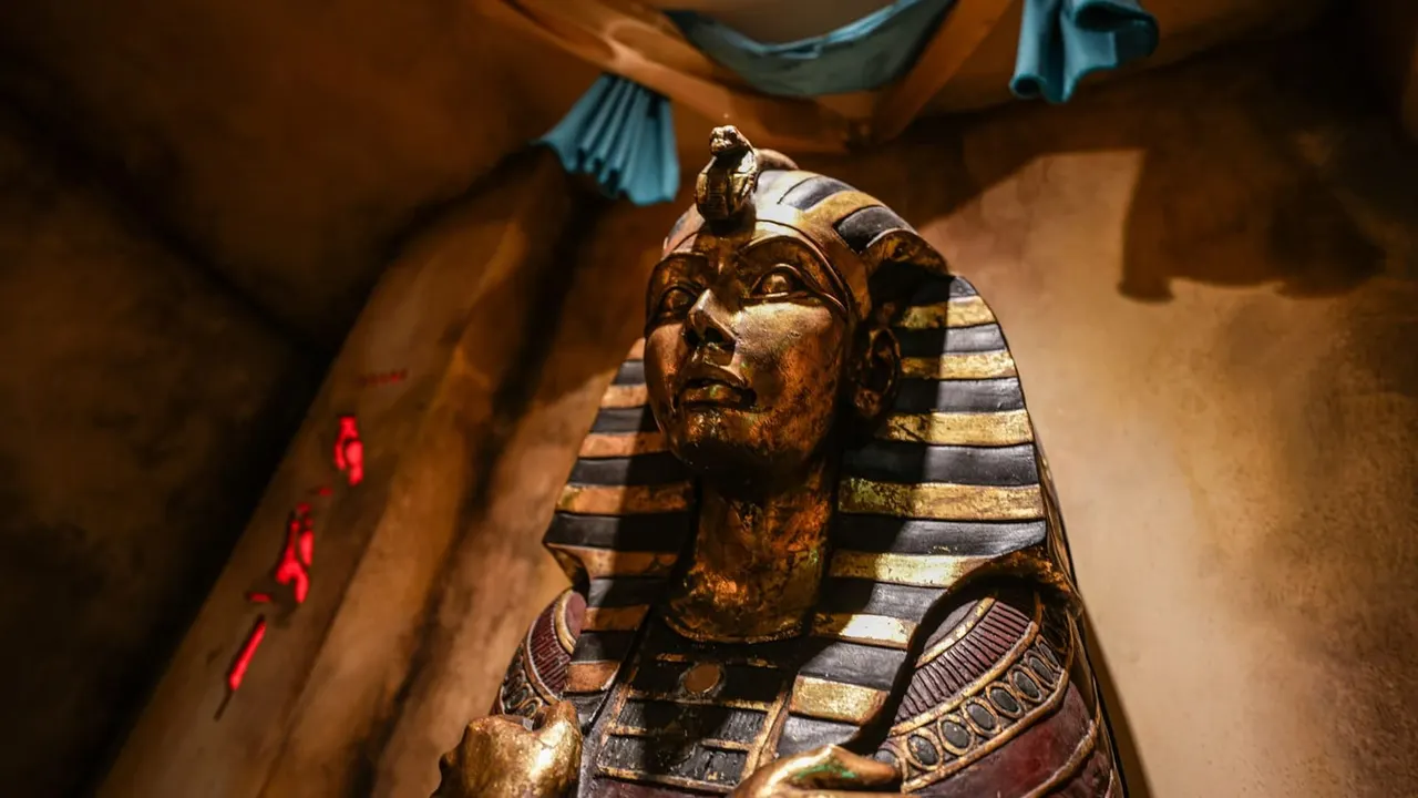 Egyptian pharaoh statue with striped headdress displayed in museum-style setting with warm lighting.