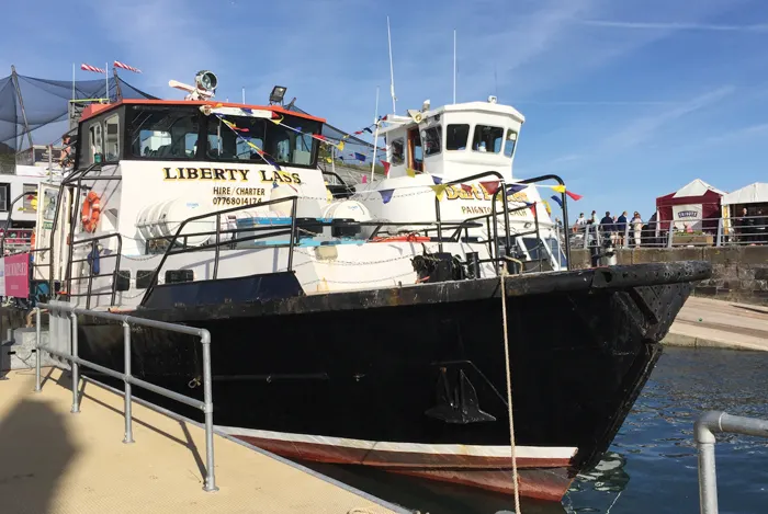 Charter boat Liberty Lass moored at a seaside dock on a sunny day.