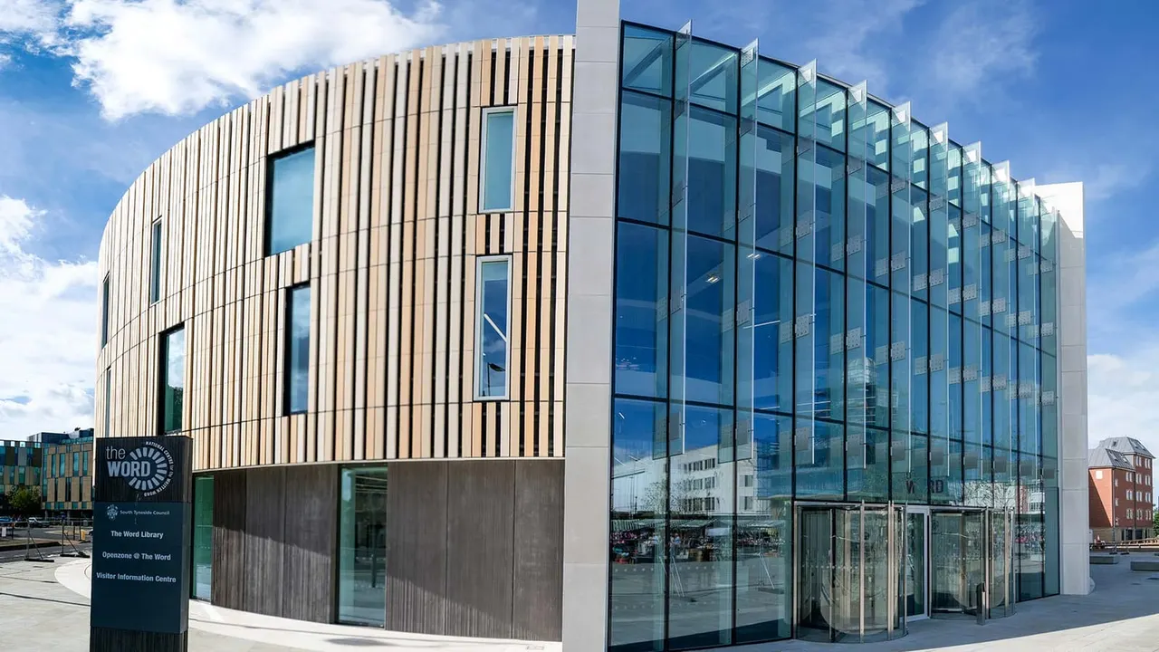 Modern curved building with timber and glass cladding, featuring "The Word" library and visitor information centre signage.