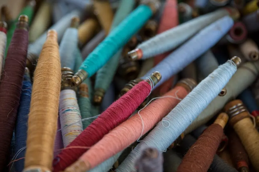 Close-up of colourful thread-wrapped pottery tools and spindles in various hues.