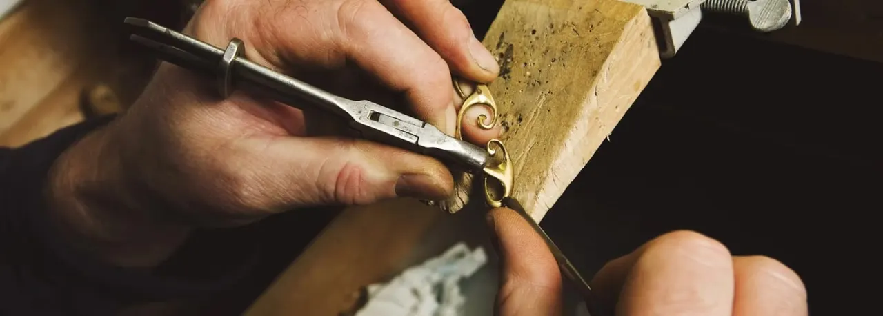 Craftsperson using chisel and hammer to carve decorative detail into stone or wood.