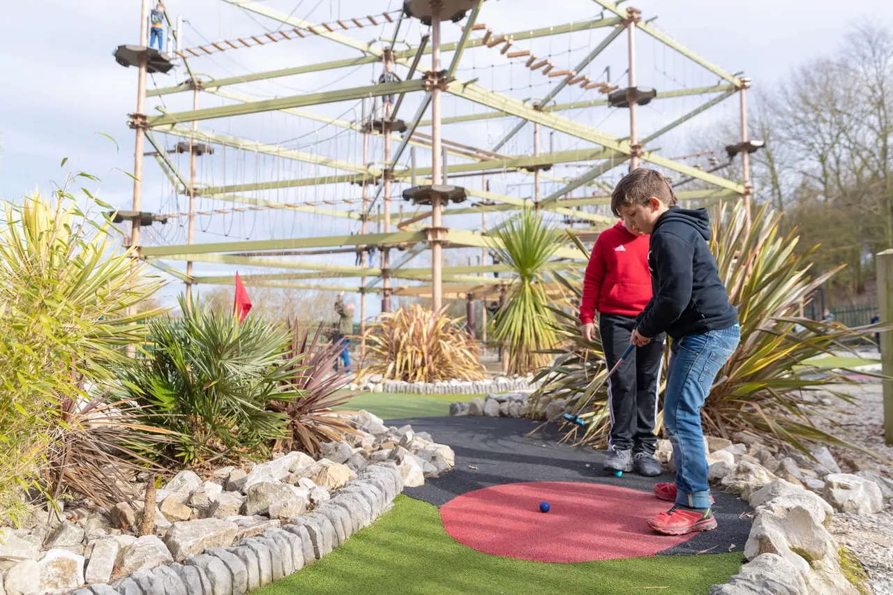 Children putting on red and green outdoor mini golf turf at Holme Pierrepont OAZ