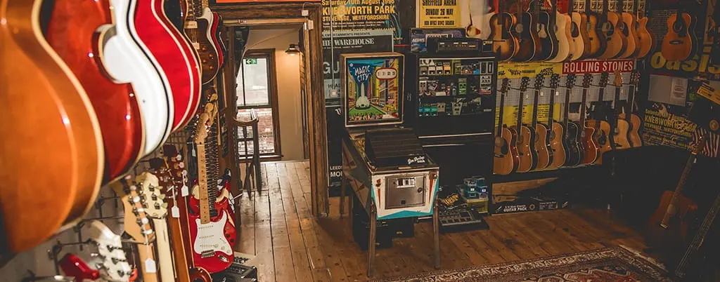 Interior of a guitar shop and café with electric and acoustic guitars displayed on walls and stands.