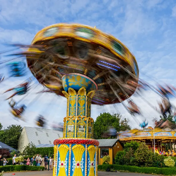 Spinning fairground ride with golden dome at an amusement park, motion-blurred passengers visible.
