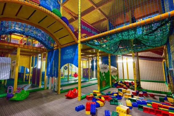 Colourful indoor play area with foam blocks, netting and climbing structures for children.