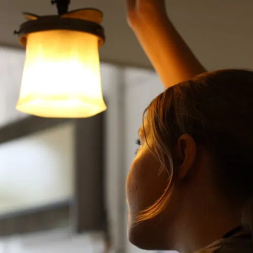 A child's face in profile, illuminated by warm light from a glowing gas lamp suspended above.