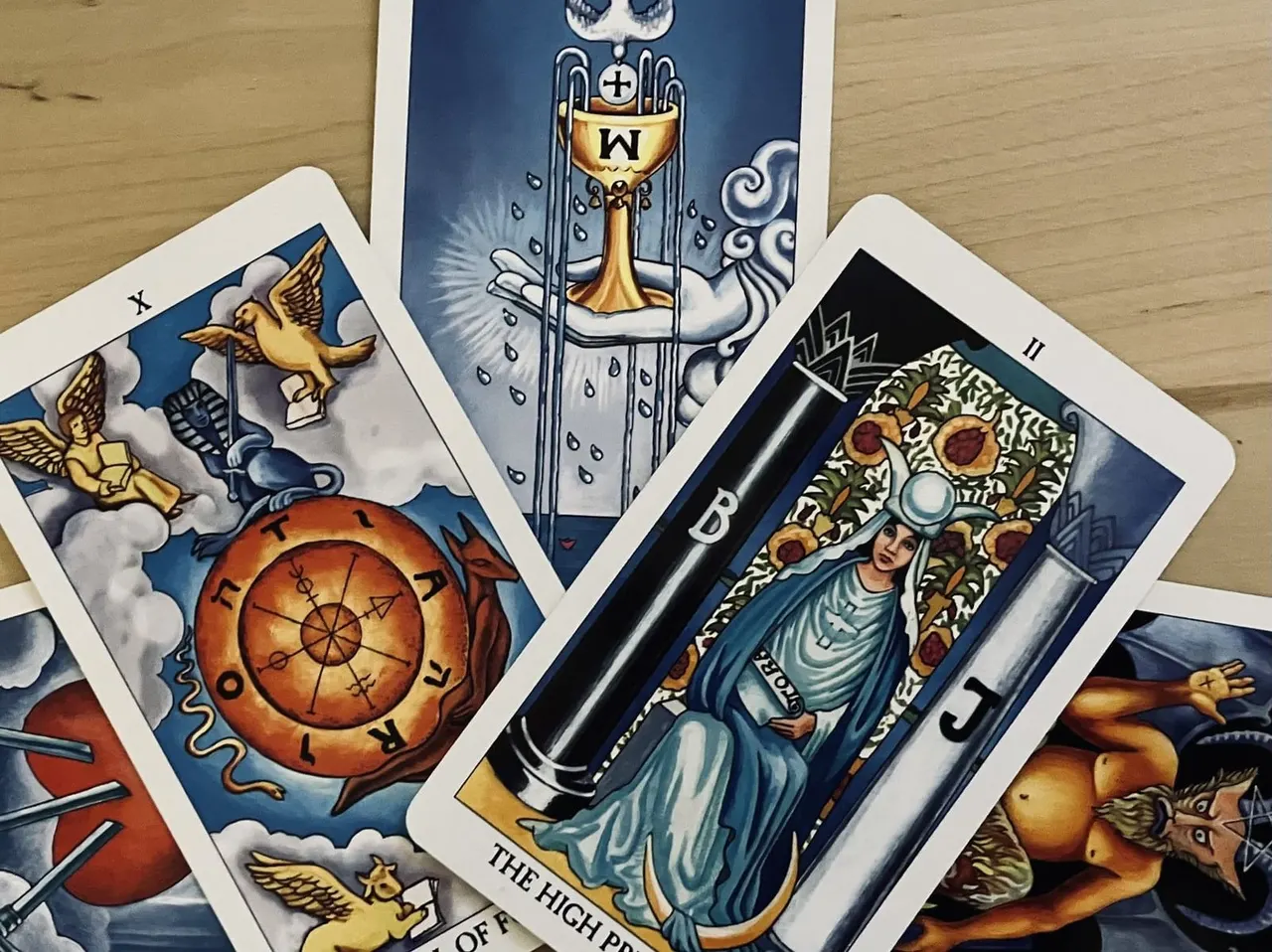 Tarot cards displayed on wooden surface, showing illustrated designs with religious and mystical imagery.