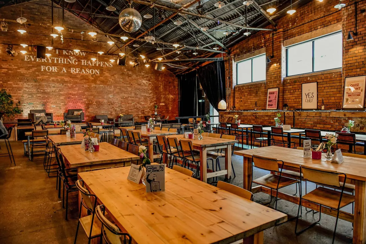 Industrial brick restaurant interior with wooden tables, mixed seating, and inspirational wall text.