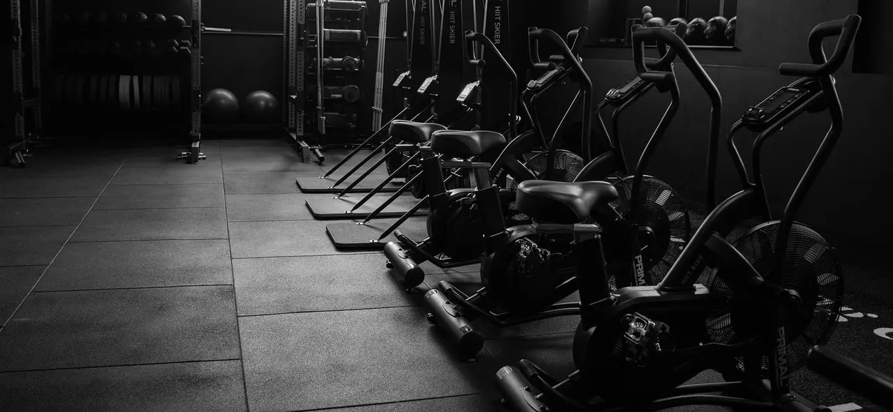 PHOTOGRAPH

Rows of stationary exercise bikes and other cardio equipment lined up in a modern gym studio.