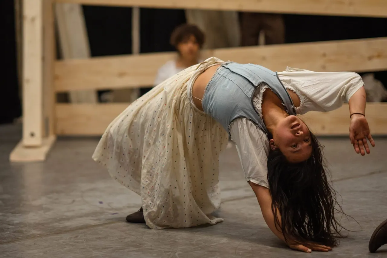 Young dancer performing a backbend on a studio floor during a contemporary dance class or rehearsal.