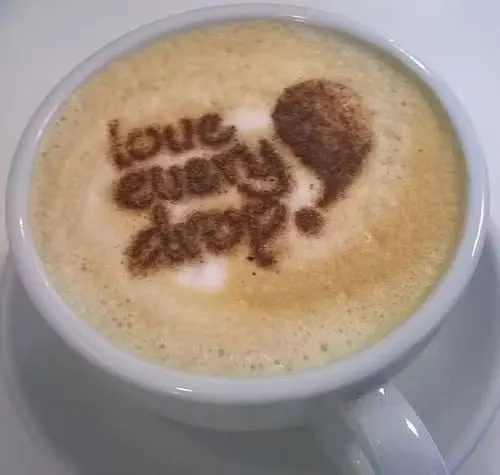 Cappuccino with latte art reading "love every day" and a heart design.