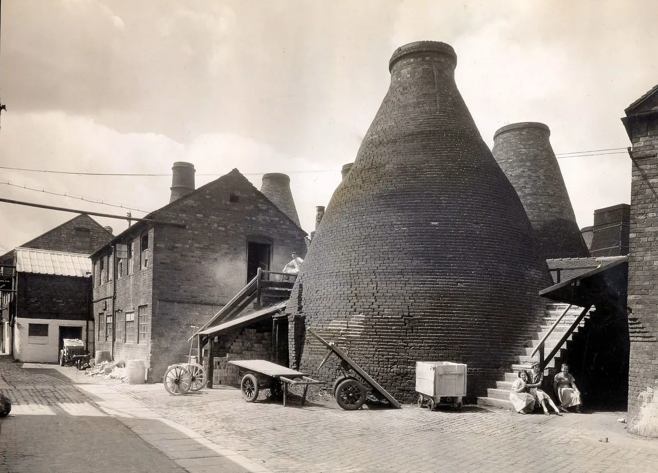 Historic pottery factory courtyard with large brick kilns and period buildings, early 20th century.