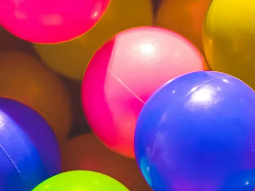 Colourful inflatable balls in bright pink, blue, yellow and green at a soft play venue.