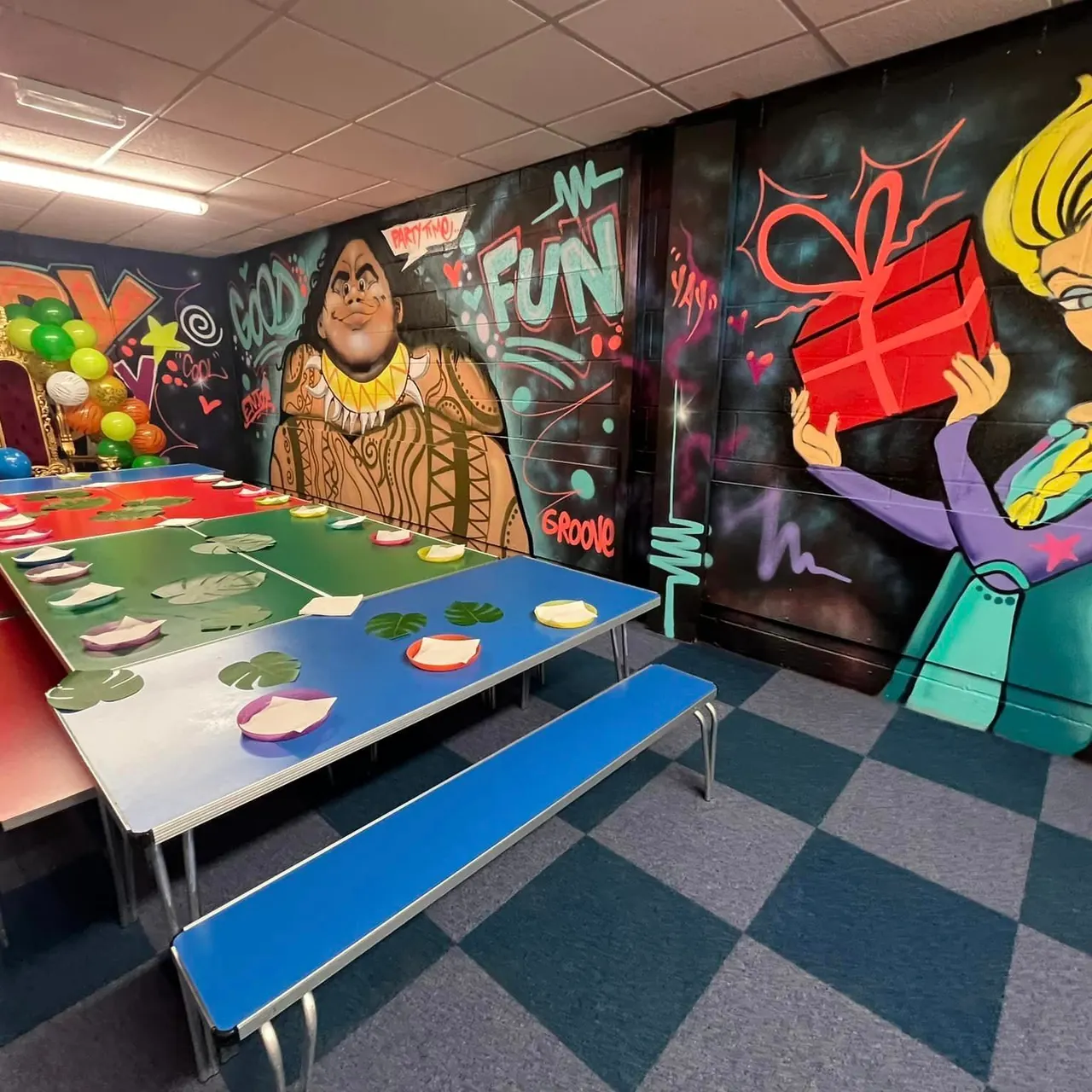 Indoor play area with colourful murals and activity tables featuring food-themed games and props.