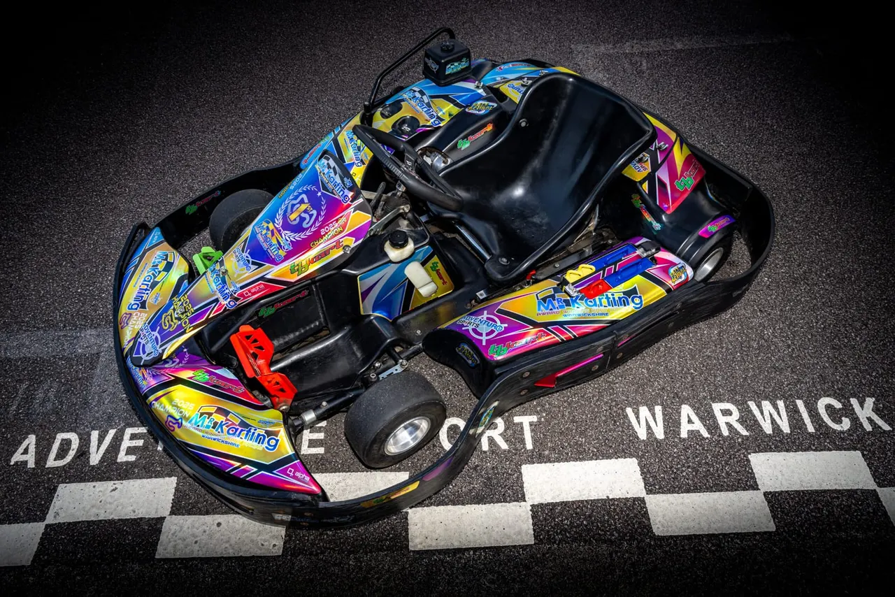 A brightly coloured go-kart with vibrant blue, yellow and pink graphics sits on a checkered finish line.