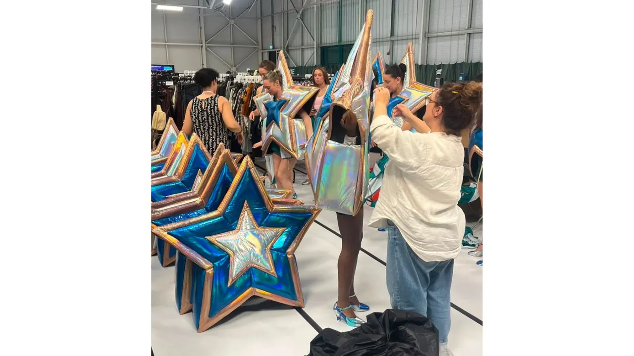 Group of people examining large inflatable star-shaped installations in an industrial warehouse space.