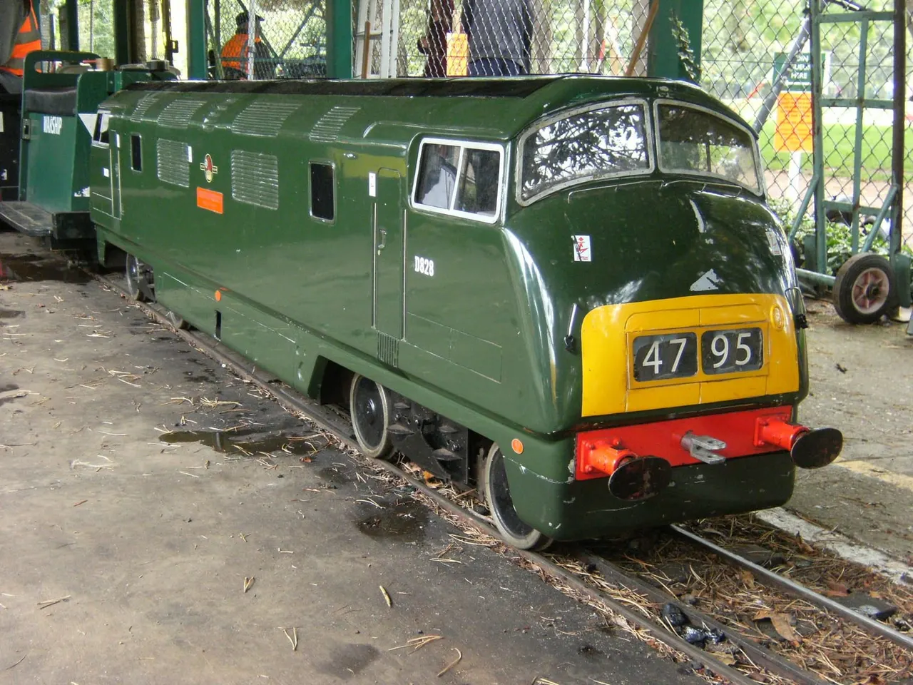 Heritage green steam locomotive numbered 4795 on miniature railway tracks indoors.