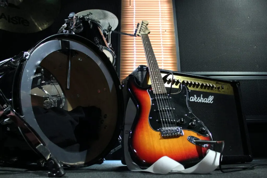 Drum kit and electric guitar with amplifier on stage.