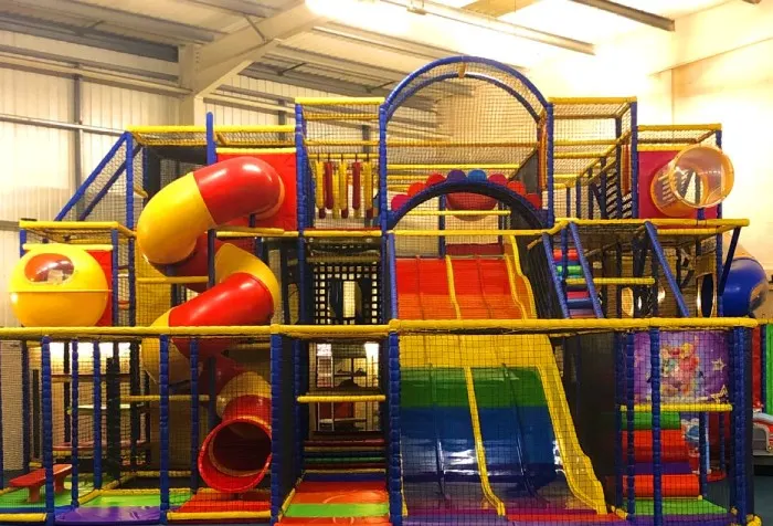 Large indoor play structure with slides, tunnels, climbing frames and ball pits in bright primary colours.