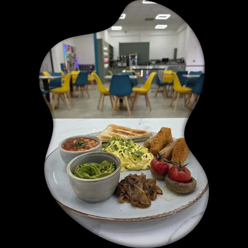 Plated meal with dips, fried items, eggs, tomatoes and bread, with soft play area and yellow chairs in background.