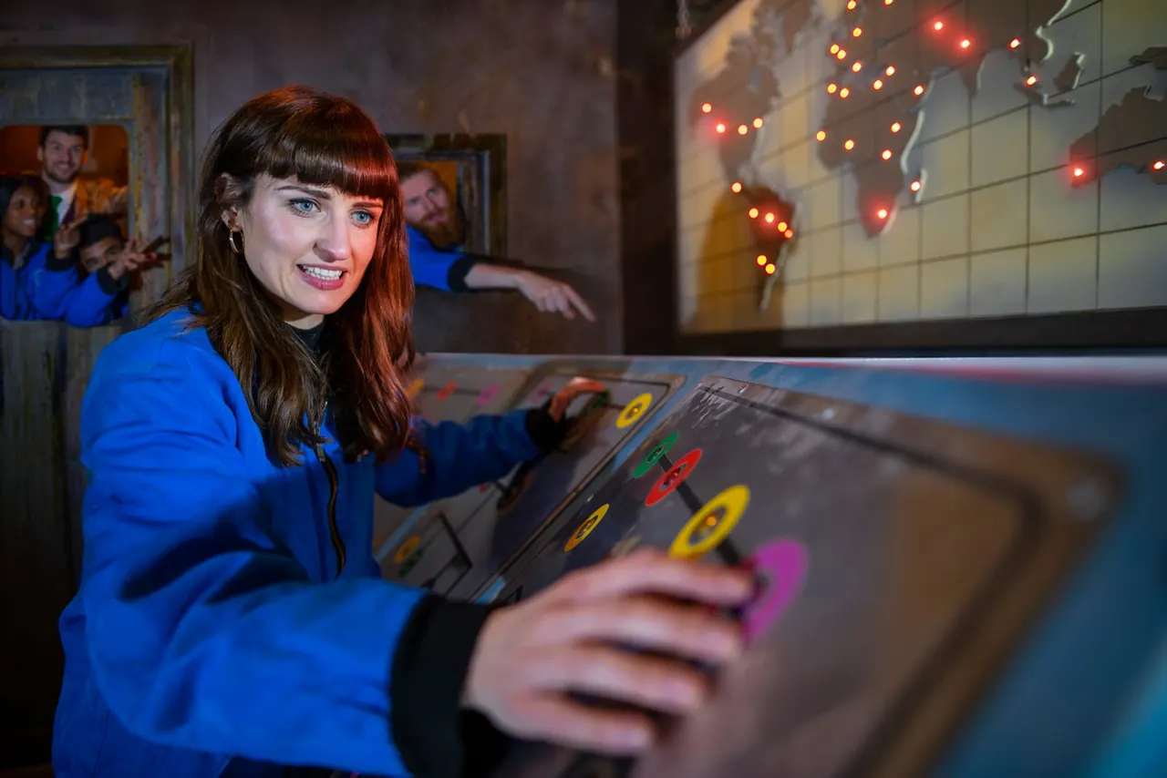 Woman in blue jacket playing an interactive game console at an entertainment venue with neon lights.