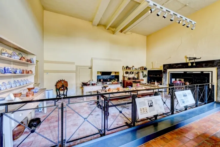 Interior of museum gallery displaying domestic pottery, tableware and kitchen items behind glass cases and barriers.