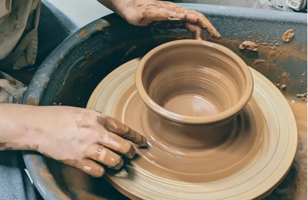 Two people shaping clay on a potter's wheel during a pottery session.