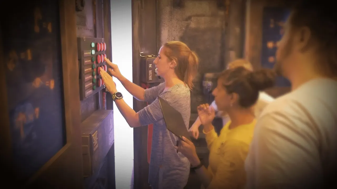 Woman pressing buttons on an illuminated control panel whilst other players observe during an escape room game.