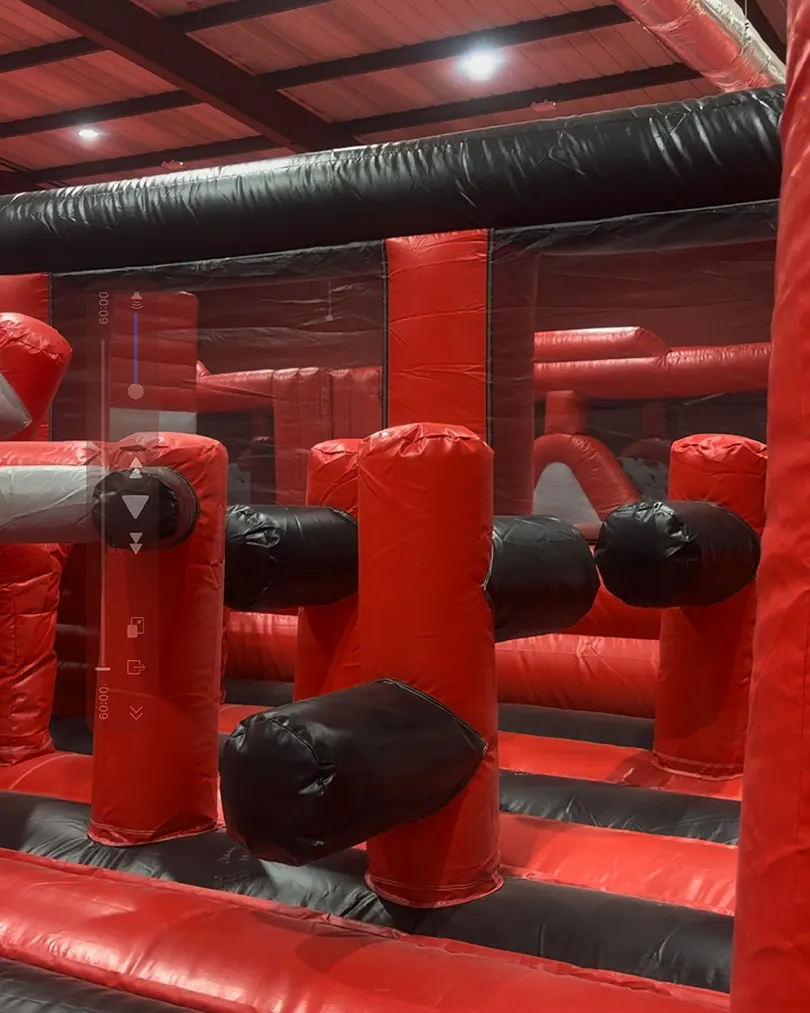 Interior of a red and black inflatable obstacle course with padded tunnels and inflatable posts.