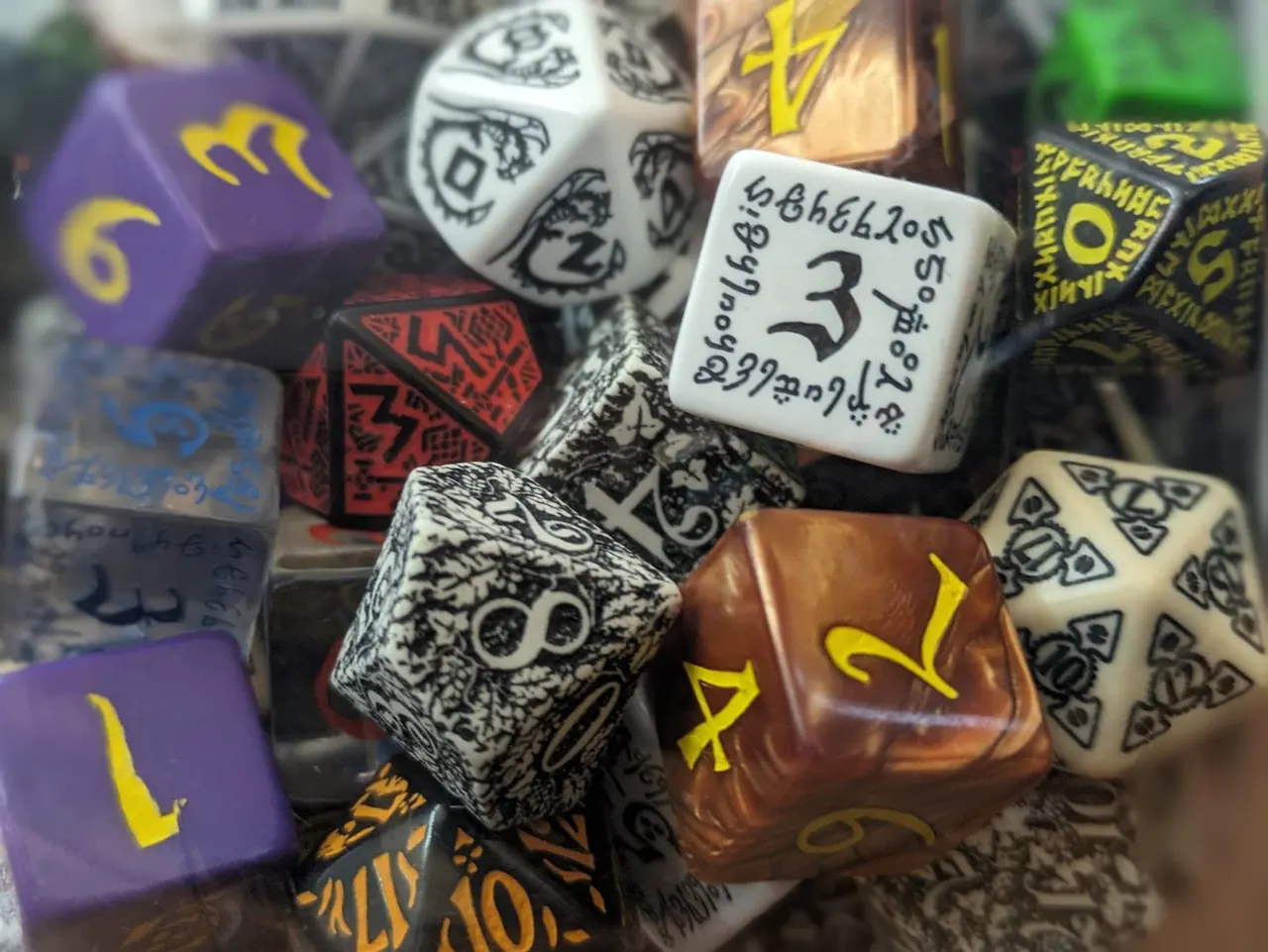 Collection of polyhedral dice in various colours and designs, used for tabletop gaming.