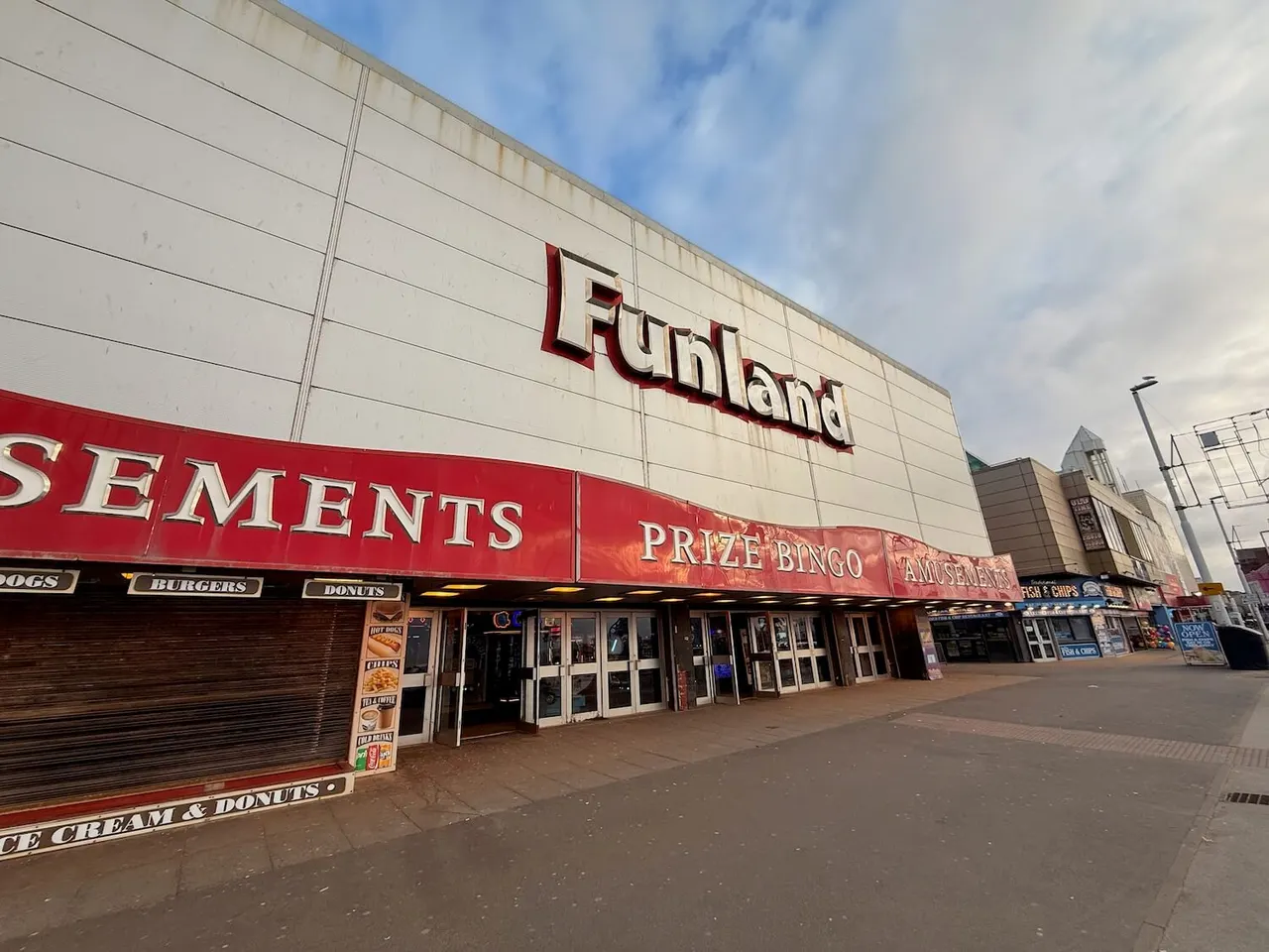 Exterior of Funland amusement arcade with red and white signage, food outlets and prize bingo advertised on the storefront.