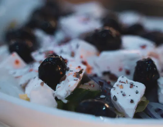 Feta cheese and olives with herbs served on a white plate.