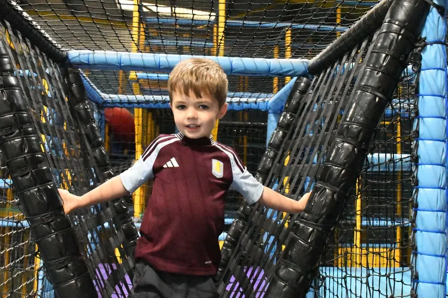 Young child navigating through an inflatable obstacle course tunnel at an indoor play centre.