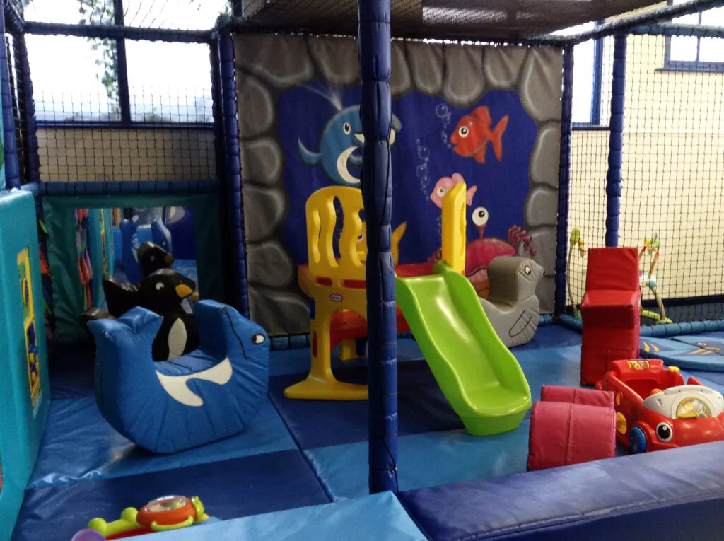 Indoor soft play area with slides, foam blocks, bean bags and colourful toys with an underwater theme.