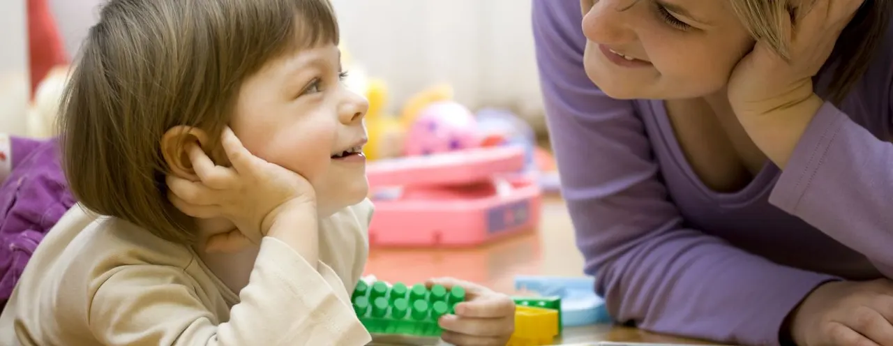 Adult and young child playing together with colourful building blocks at an indoor play centre.