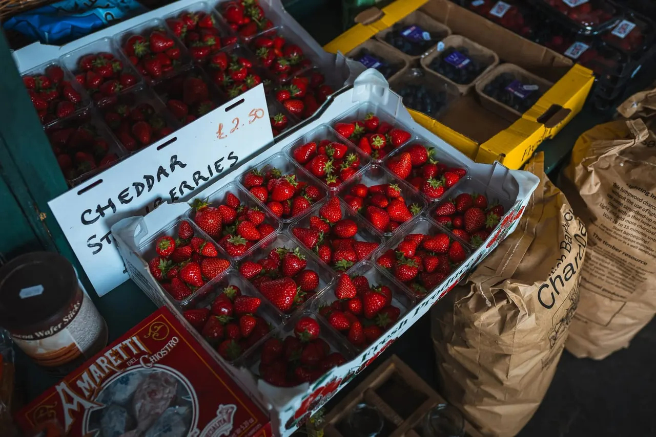 Strawberries in clear plastic containers displayed for sale at a farm shop market stall.