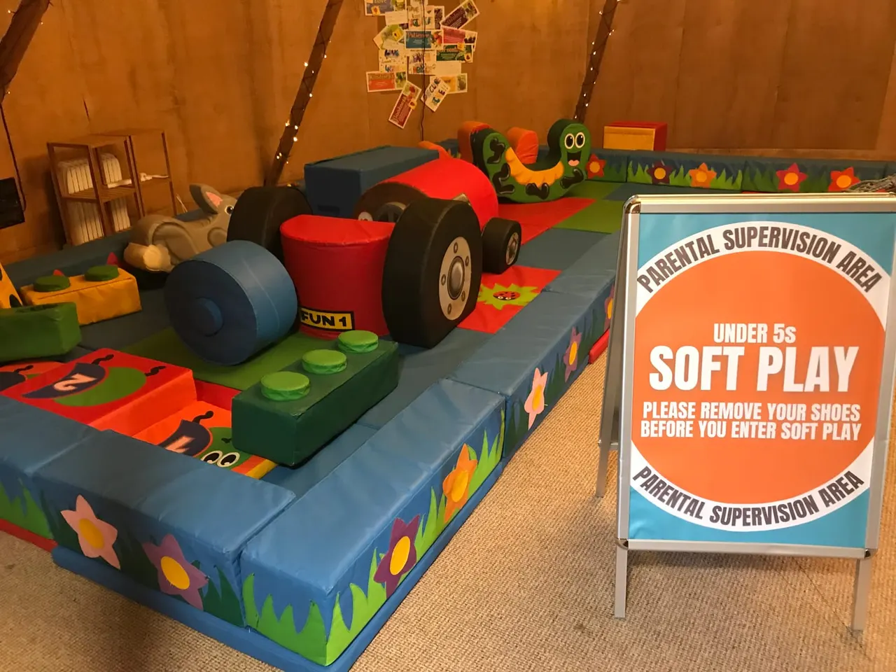 Colourful soft play area for under-5s with foam play equipment including a red racing car, blue ball, and themed decorations.