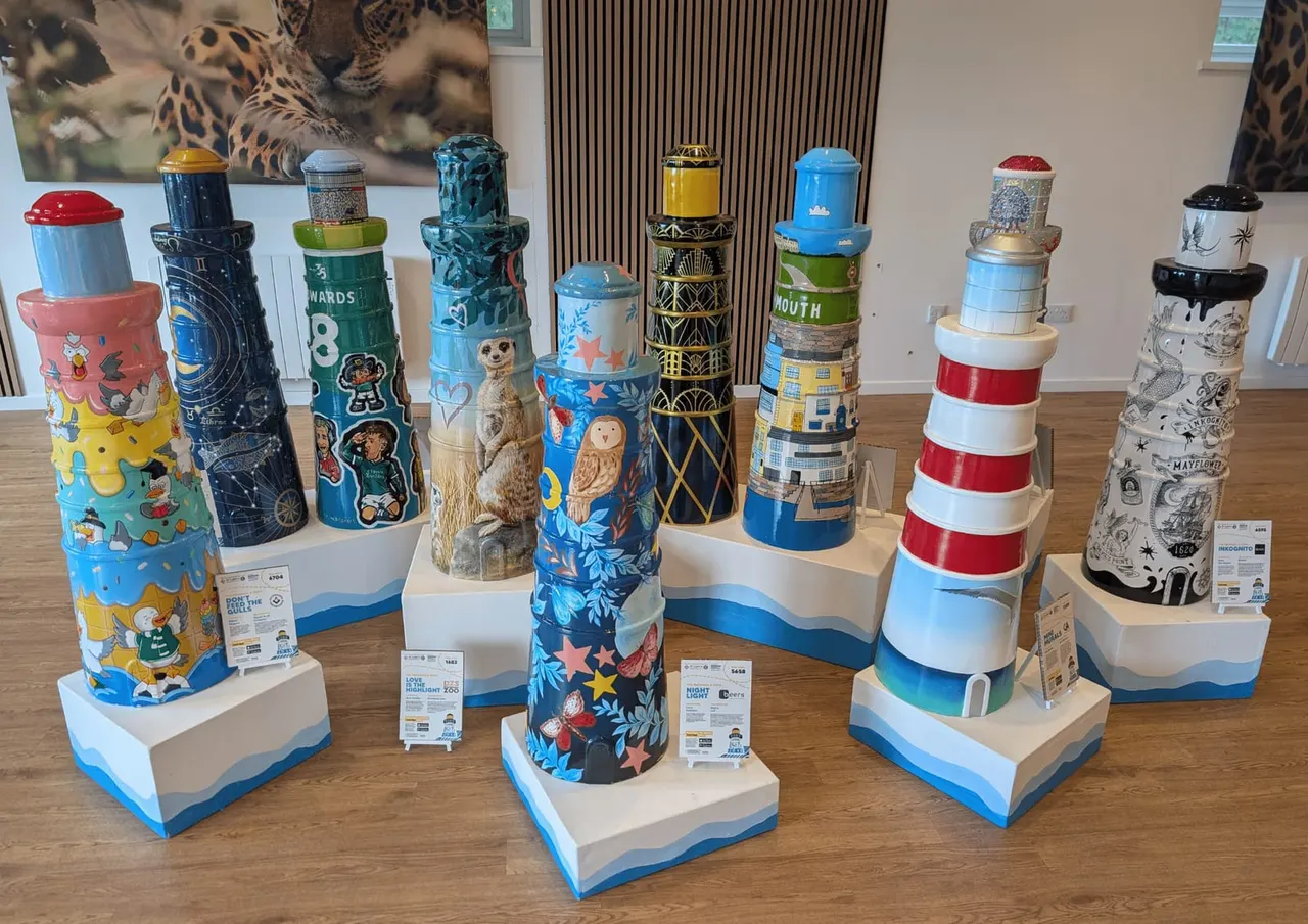 A collection of decorated lighthouse models on display pedestals in an indoor exhibition space.
