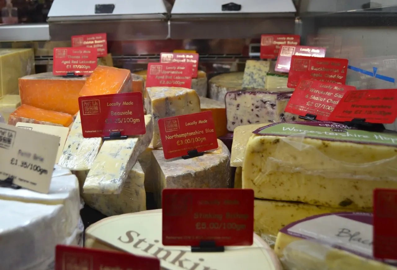 Display of locally made cheeses with red price labels in a farm shop counter.