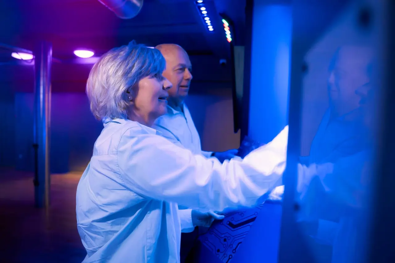Two people playing an interactive arcade game under blue and purple neon lighting.